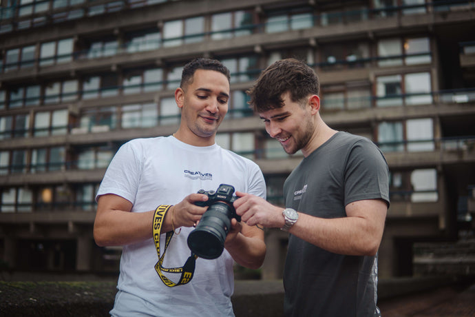 2 creatives club members checking a image on a dslr camera smiling